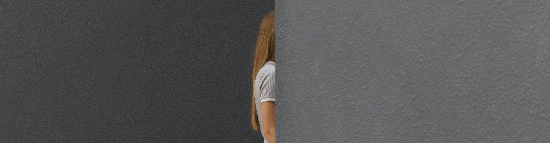 Blond girl hiding behind a wall 